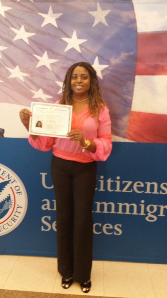 A woman holding up her certificate in front of an american flag.